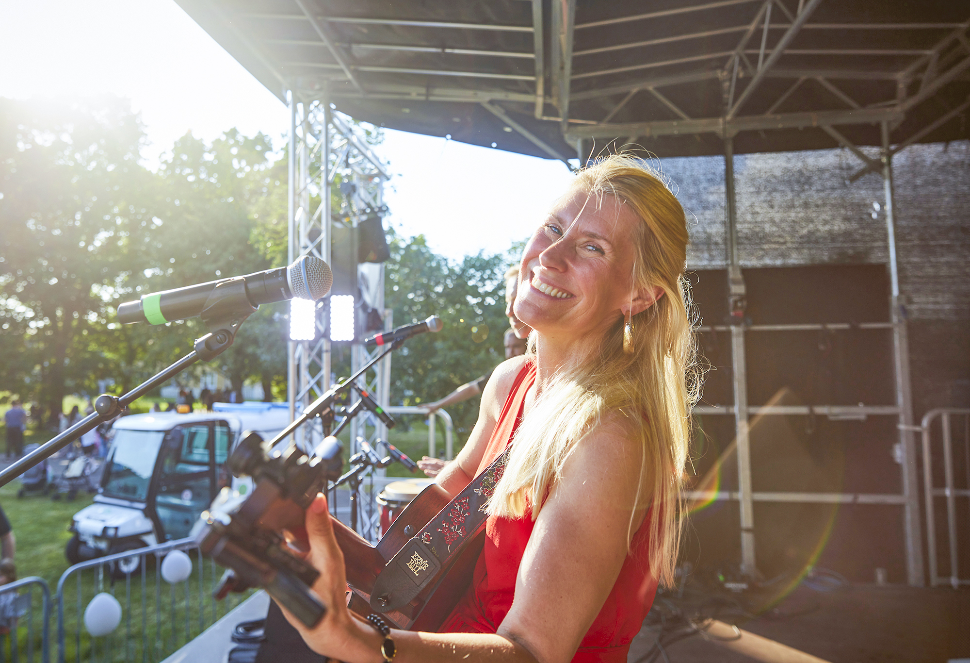 Linda står på scenen med gitarren i handen och kollar in i kameran