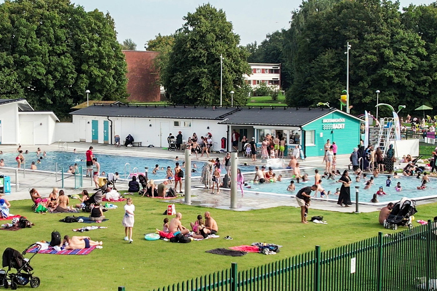 Många människor solar och badar vid poolen.