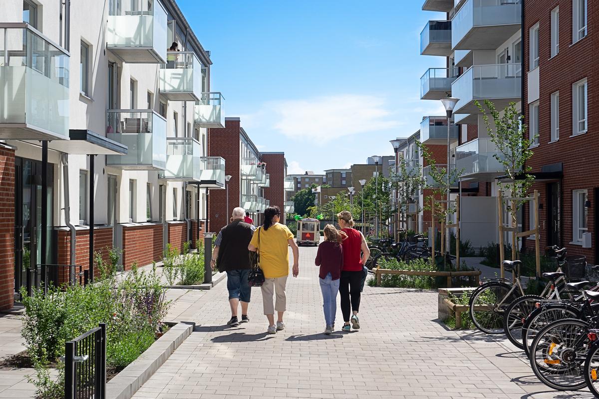 Fyra personer går på gatan mellan husen